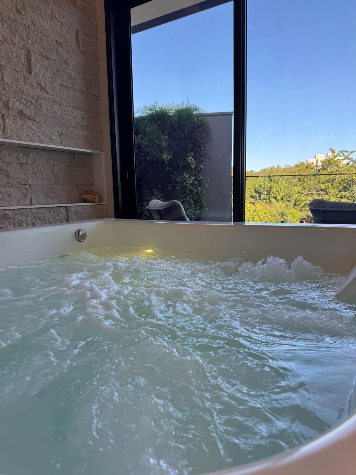 Banheira de hidromassagem em funcionamento com vista para o jardim