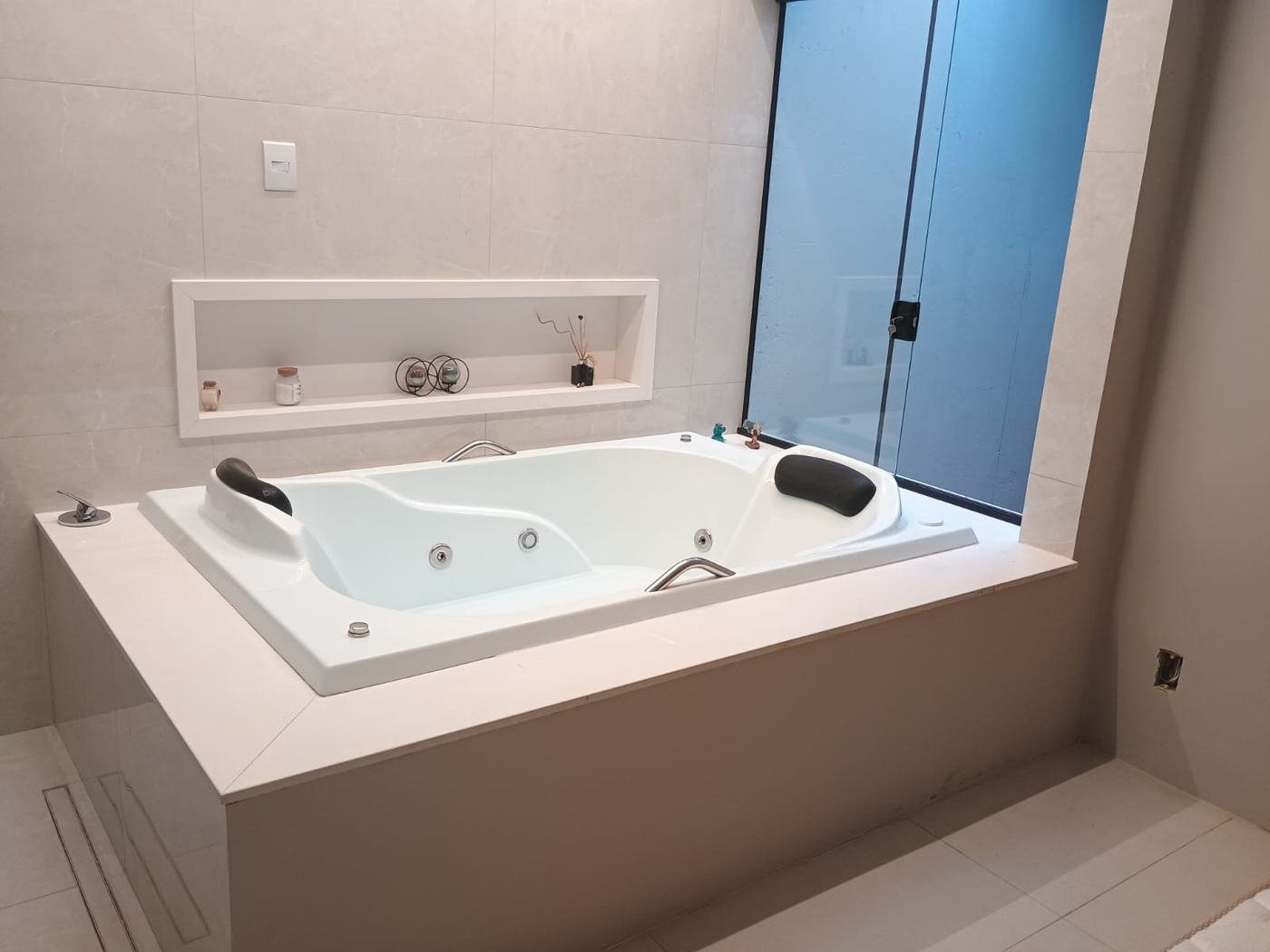 Banheira retangular de hidromassagem em suíte com revestimento claro